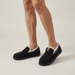 Black house loafers worn by a model, front view on a studio background